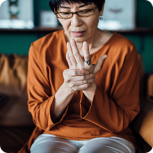 older woman holding and rubbing hand indicating pain