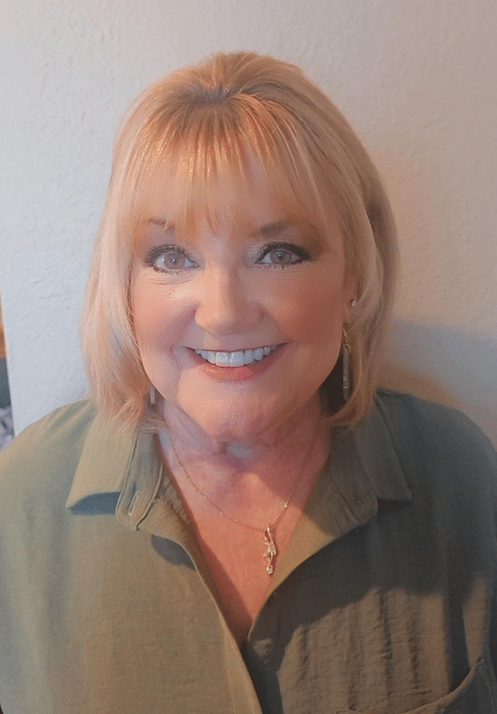 Smiling woman with blonde hair in a green shirt, exuding warmth and approachability.