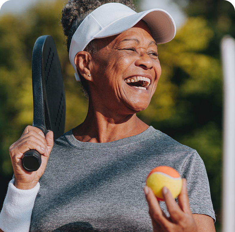 woman enjoying a game of pickleball, holding the racket with her right hand and ball in her left.